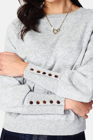 Wide sweater with round neckline and slightly puffed long sleeves with button placket at the bottom of the sleeve