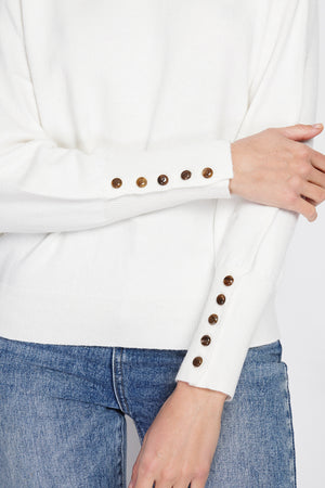 Wide sweater with round neckline and slightly puffed long sleeves with button placket at the bottom of the sleeve
