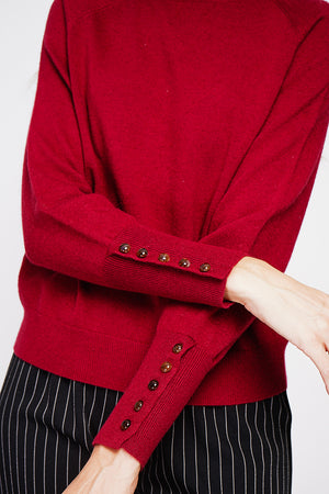 Oversized turtleneck sweater with button placket at the bottom of the long sleeves